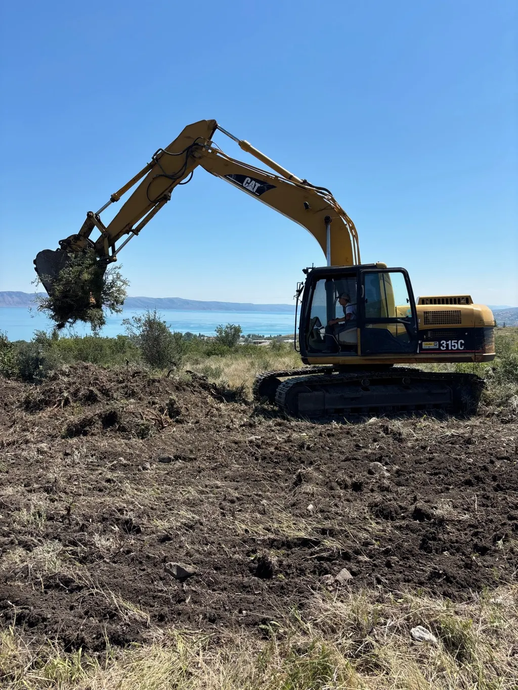 An excavator clearing sagebrush from a building lot above Bear Lake